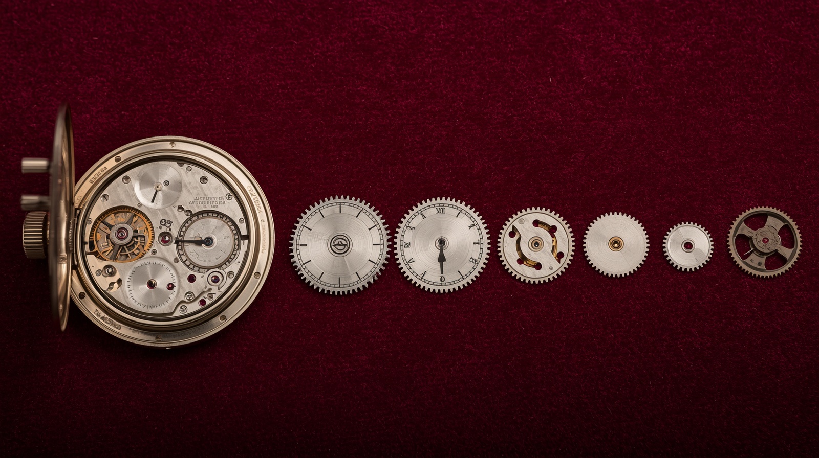 A mechanical watch movement mid-disassembly on a velvet surface